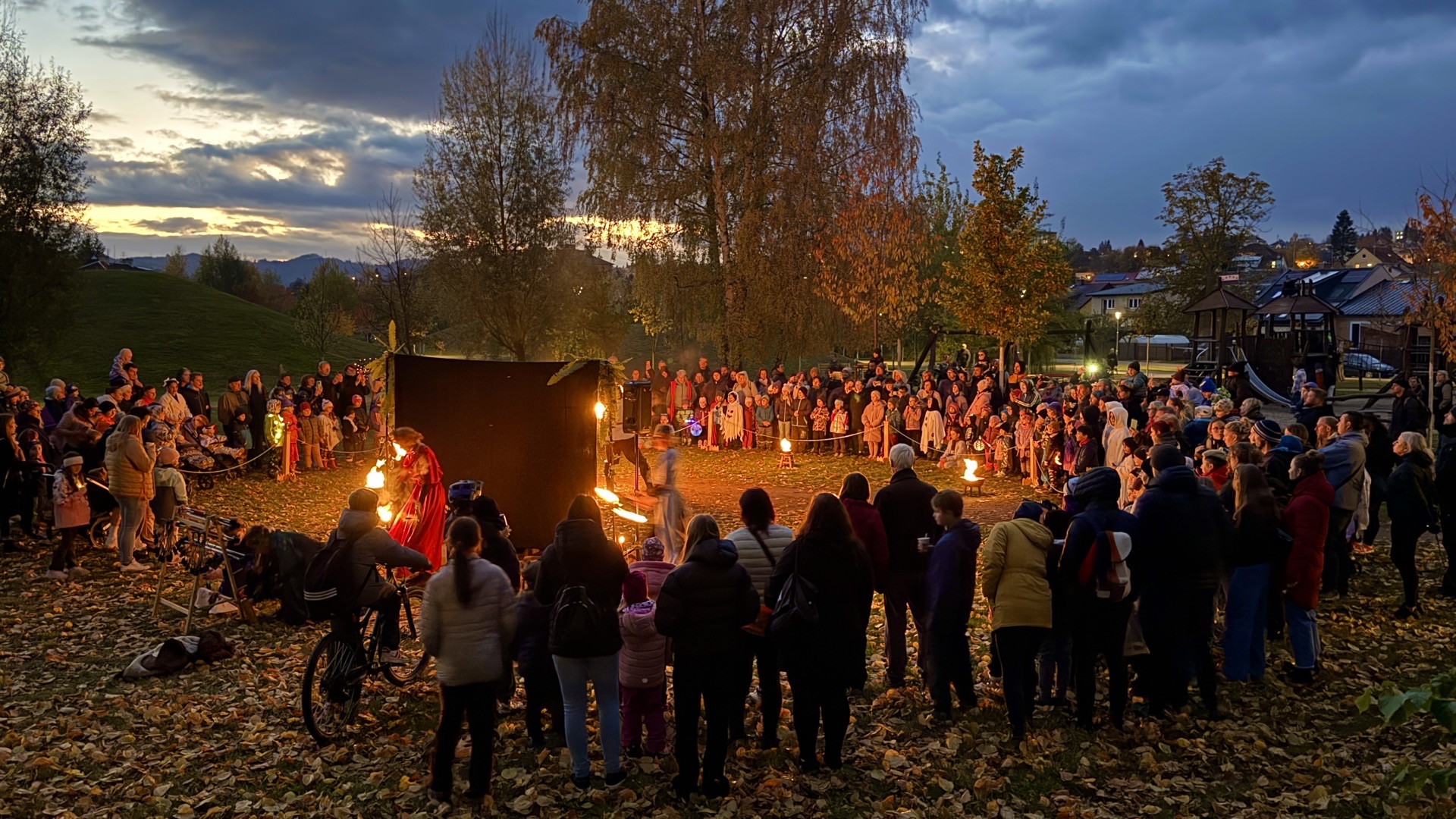 Kruh diváků kolem ohnivé show za soumraku
