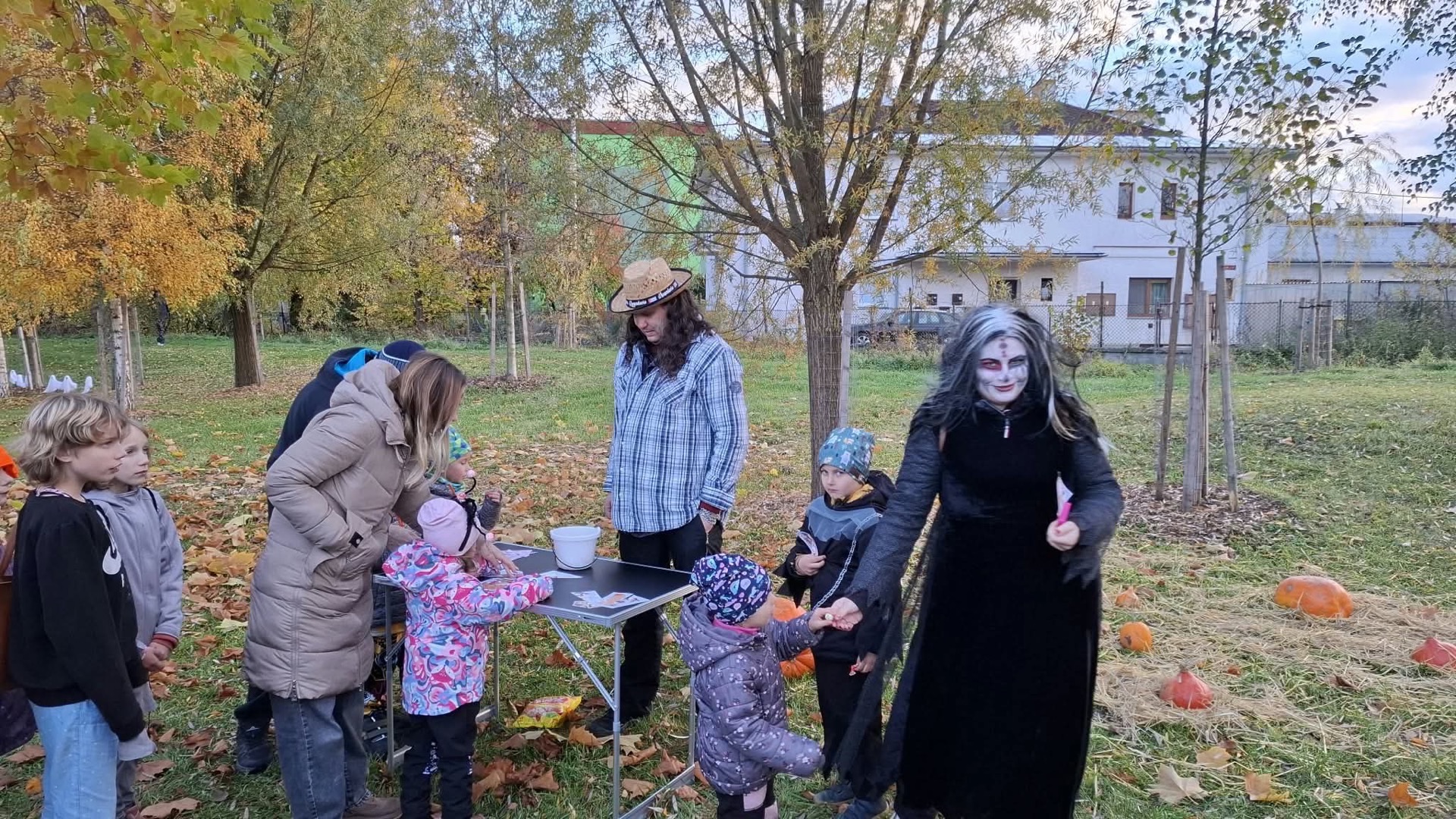 Čarodějnice u stolku s kartičkami podává dětem odměnu
